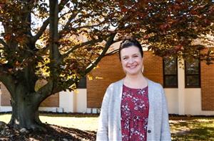 Lorri Batsie smiles for the camera in front of a tree 