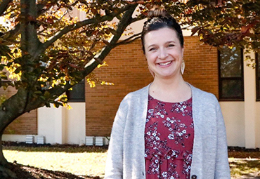  Lorri Batsie smiles for the camera in front of a tree